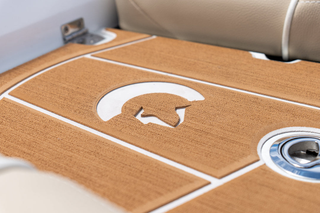 Close-up of a boat's wooden floor with a logo and metallic accents.