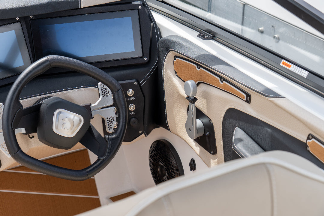 Close-up of a boat's steering wheel and dashboard with a focus on the controls.