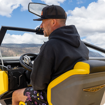 Man sitting inside an open-top vehicle with a scenic background