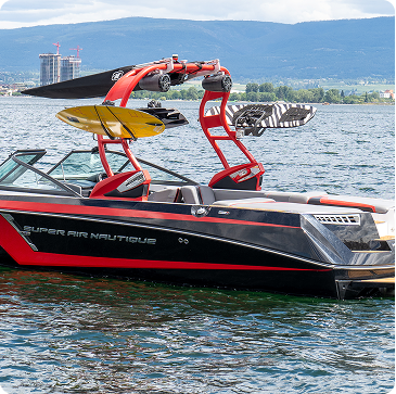 Red and black Super Air Nautique boat with wakeboard tower on a body of water.