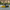 Yellow and black boat on a lake with trees in the background