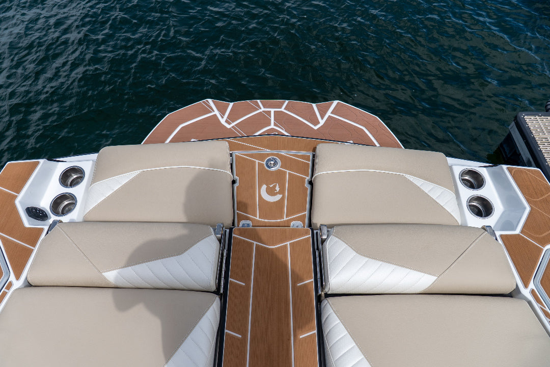 Boat deck with beige cushioned seats and brown center console on water